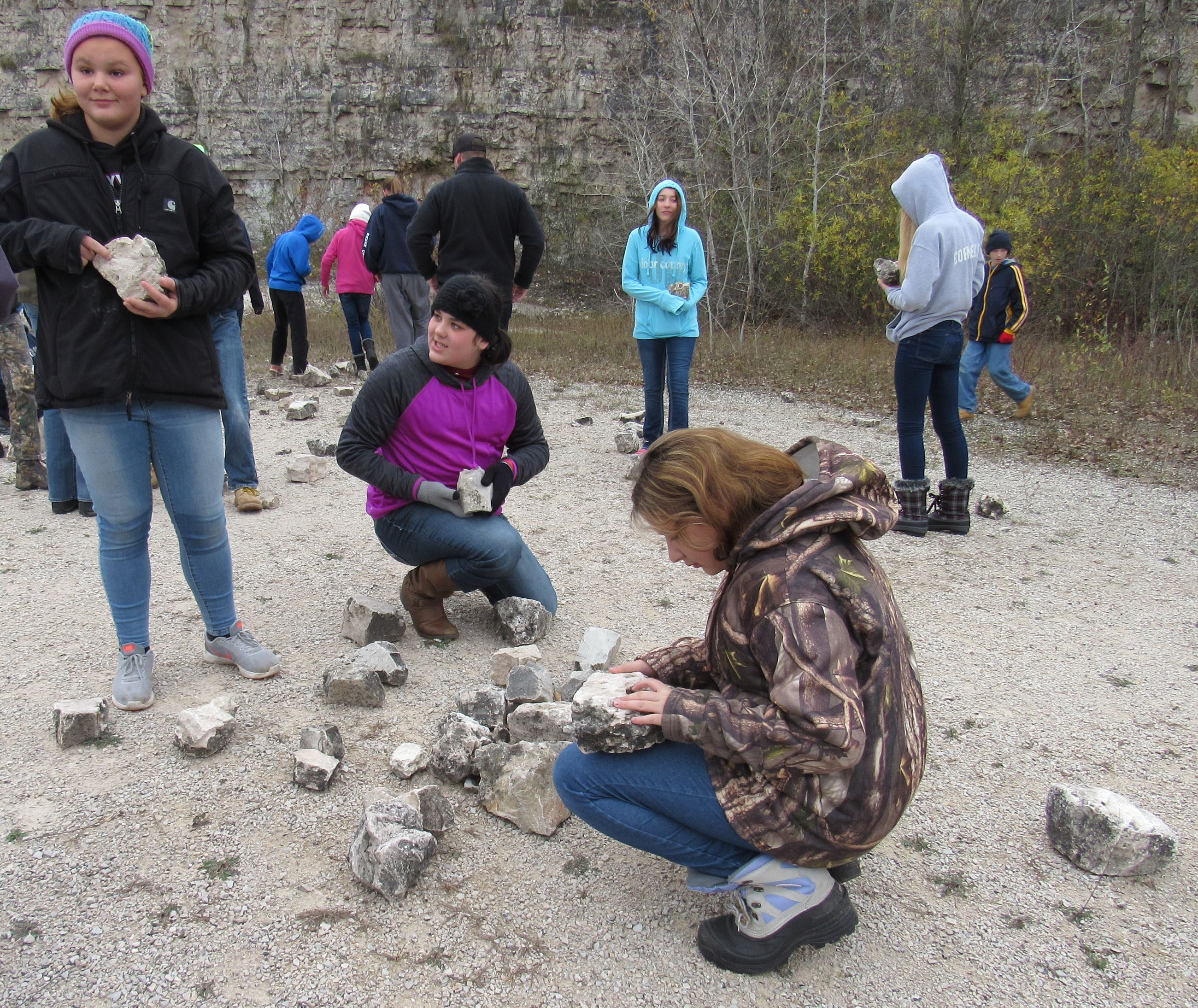 Teens looking at rocks with fossils in them in a quarry